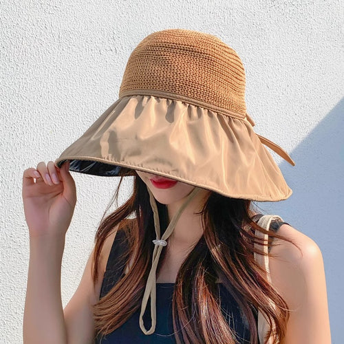 Woman wearing a beige sun hat against a light background
